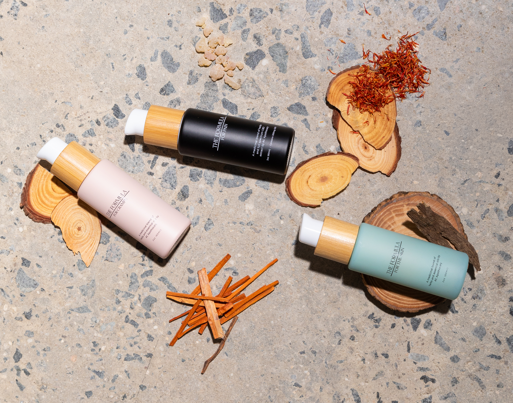 Three skincare bottles with natural elements on a textured surface